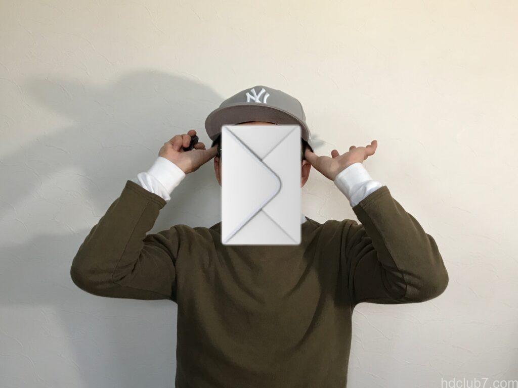 購入直後のニューエラのキャップ59fiftyの両こめかみに親指を突っ込んでいる人