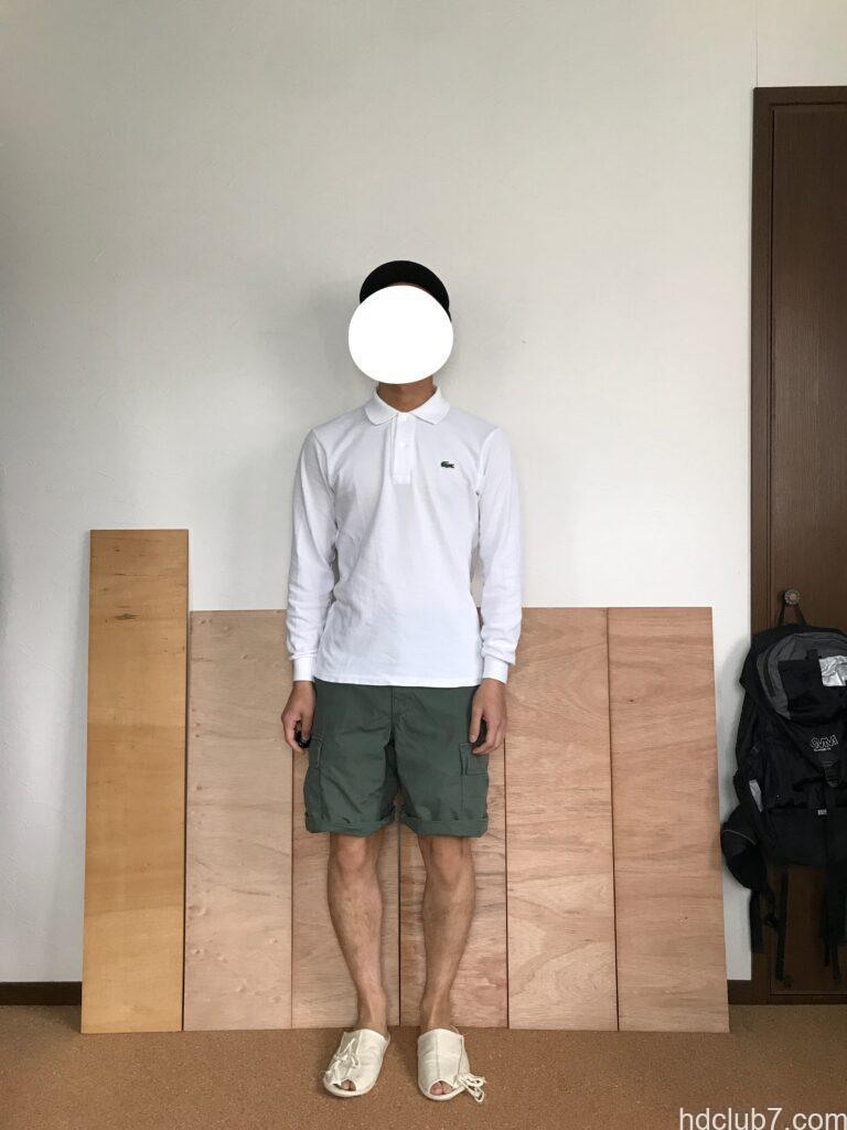 ロールアップしたプロッパーのBDUカーゴショーツとラコステの長袖ポロシャツを着て立っている男